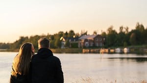 Carbon-neutral district heating. A couple sitting by the water, leaning on each other.