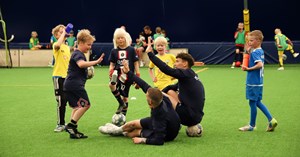 AC Oulun pelaaja heittää ylävitoset jalkapalloa pelaavien lasten kanssa. 