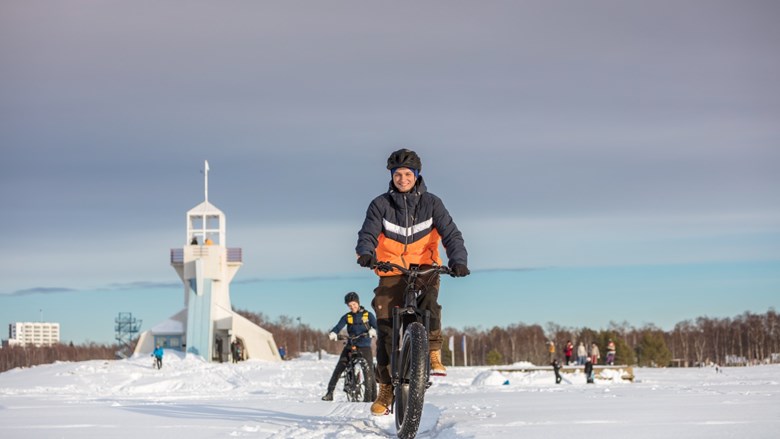 Talvipyöräilijät Nallikarissa. Aurinko paistaa ja ihmiset hymyilevät.