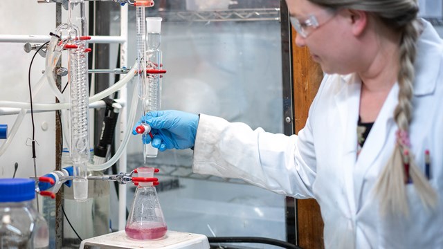 A researcher in a laboratory uses a pipette to put liquid into a test tube.