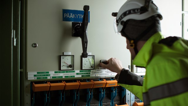 An employee of Oulun Energia in front of a fusebox.