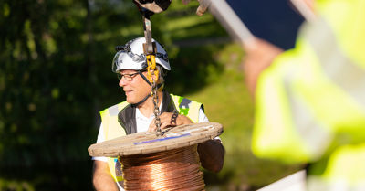 An employee of Oulu Energy is guiding where to put a roll of cables.