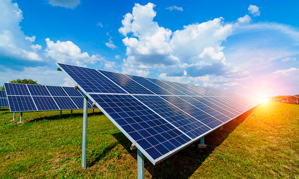 Solar panels are placed on the lawn, and the sun shines behind them.