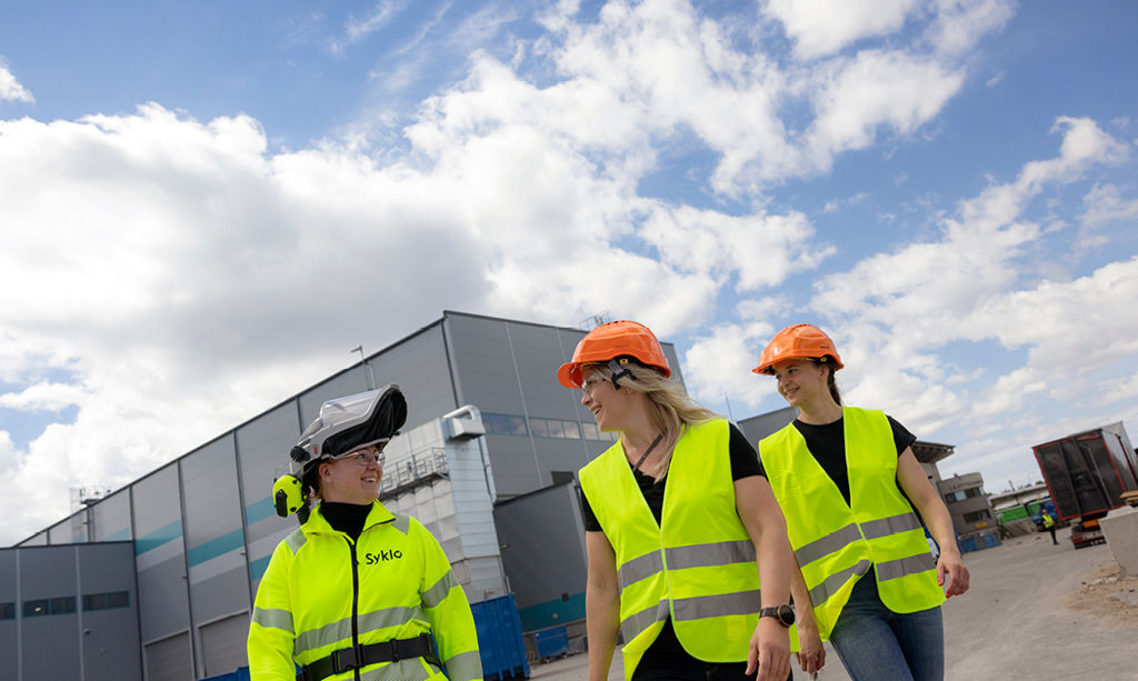 Three Syklo employees walk around the sorting plant in Rusko.