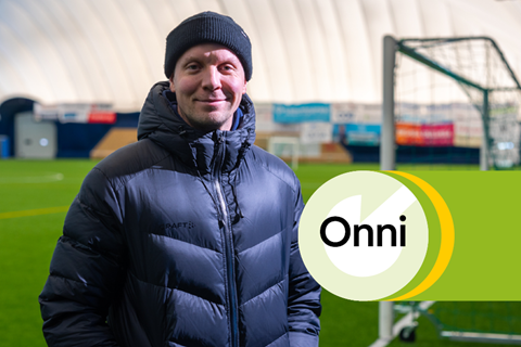Juho Meriläinen is standing in the foreground and the Garam Masala football hall can be seen in the background. On top of the picture there is green element of Onni district heat.