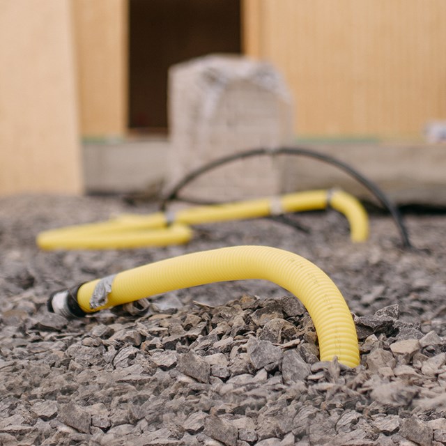 Kaukolämmön nousukulma näkyy omakotitalon rakennustyömaan pihalla kivien keskellä.