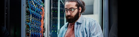 A man concentrates on the computer screen in the server room.