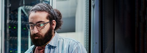 A man looks at the computer screen in the server room.