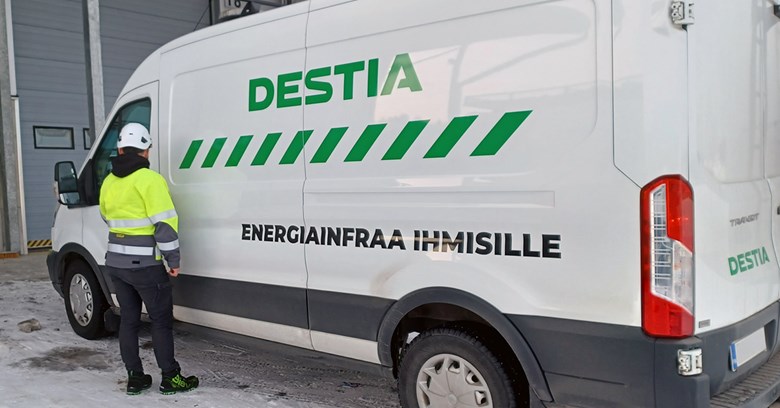 Destian työntekijä seisoo työvaatteissa selin kameraan Destian pakun edessä.