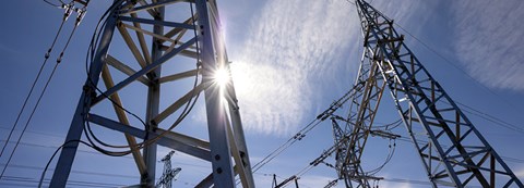 Electricity towers pictured from below. Almost clear sky as a background.