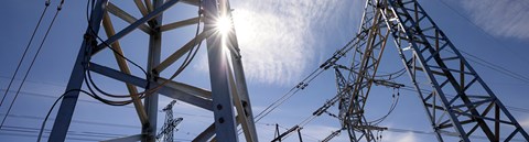 A ray of sunsihne shines through electricity tower.