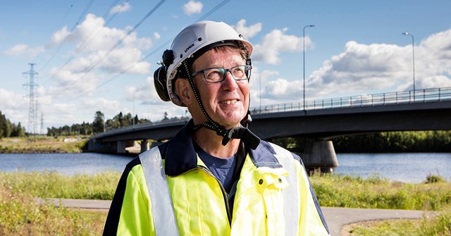 Oulun Energian työntekijä katsoo oikeaan yläviistoon Oulujoen edessä.