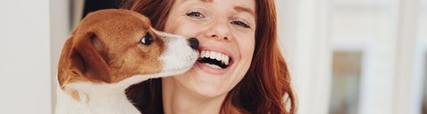 Woman is smiling and holding a puppy.