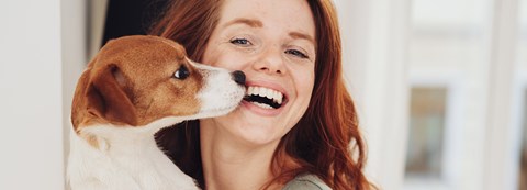 A smiling woman is holding a puppy.