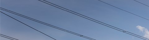 Sähkölinjoja kuvattuna sinistä, pilvetöntä taivasta vasten.