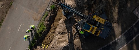 Aerial view of the construction site. There are four Oulun Energia employees and an excavator on site.