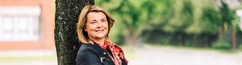 Sustainabilityleader Katja Virkkunen leans to a tree.