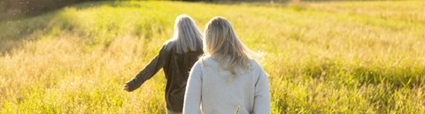 Two young women are running on hayfield on a sunny day.