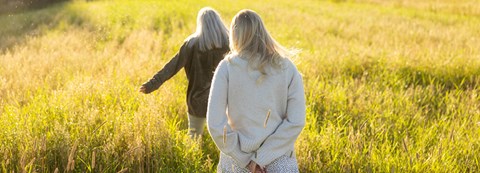 Two young women are running on a hayfield on a summer day.