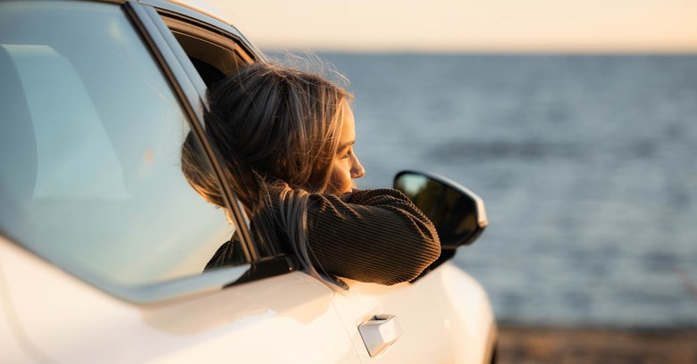 Young person is looking out of a car window.