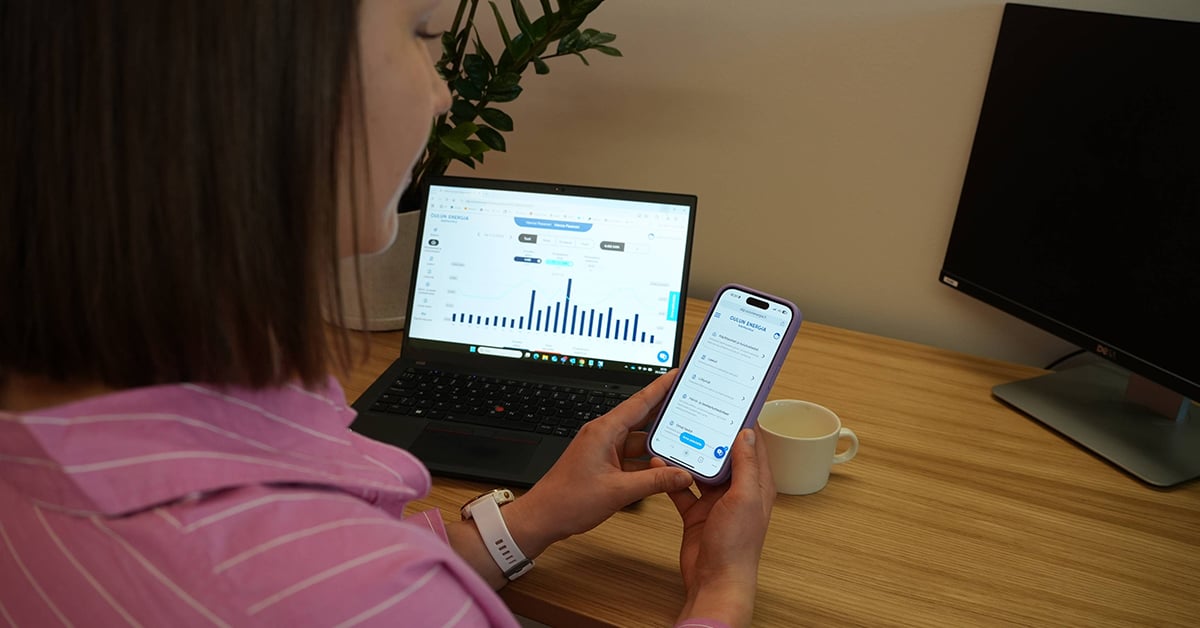 Kuvassa henkilö selaa Oulun Energian mobiilisovellusta puhelimelta. Näkyvissä on myös tietokoneella OE Digipalvelu. 