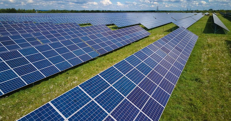 Aurinkopaneeleja on rivissä pellolla ja ne muodostavat aurinkovoimapuiston. 
