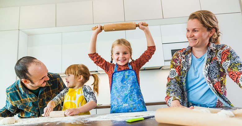 Family of four are baking together in a kitchen.