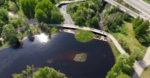 Ilmakuvaa Oulun Hupisaarilta, jossa näkyy veden pintaa, teitä ja puita. 