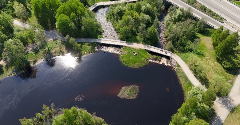Ilmakuvaa Oulun Hupisaarilta, jossa näkyy veden pintaa, teitä ja puita. 