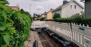 Kuva kadulta, jossa on meneillään kaukolämpöverkon saneeraustyö. Tie on piikattu auki ja suojattu aidoin. 