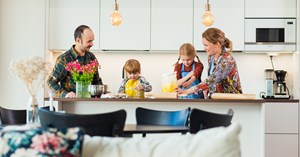 A family of four bakes together by the kitchen island.