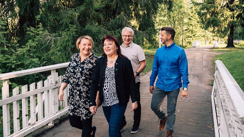 Neljä Oulun Energian lämpöpalveluiden työntekijää kävelee Ainolan puiston sillalla.