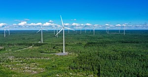 The aerial image shows wind turbines in a Finnish forest landscape.