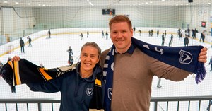 AC Oulun toimitusjohtaja Hanna Väänänen ja Oulun Kärppien myyntijohtaja Ilkka Mikkola hymyilevät Raksilan harjoitushallissa. Taustalla lapset pelaavat jääkiekkoa.