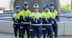 Käytön kesätyöntekijät seisovat rivimuodostelmassa siilon edessä.