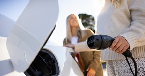 Two young women are charging electricity in to their white car.