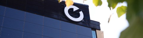 The image shows Oulu Energia’s O symbol, a key brand element, mounted on the exterior wall of the building. Also visible are solar panels installed on the office building’s façade.