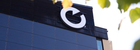 The exterior wall of an Oulu Energia office building is shown from the outside. Mounted on the wall are the O symbol, a key brand element, and several solar panels.