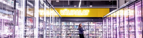 Osuuskauppa Arinan työntekijä kävelee kylmäkaappien välissä. 