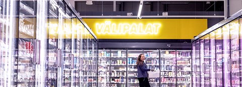 Osuuskauppa Arinan työntekijä kävelee kaupassa kylmäkaappien välissä. 