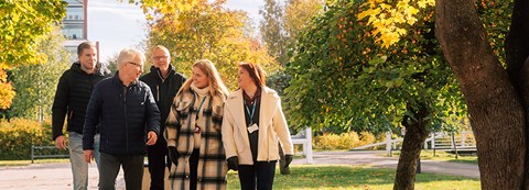 In autumn, employees of the heating services walk in the park amidst the autumn bush and talk to each other.