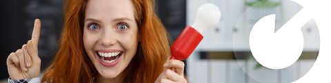 A young woman with red hair holds a red light bulb in her hand, looks at the camera and looks stunned.