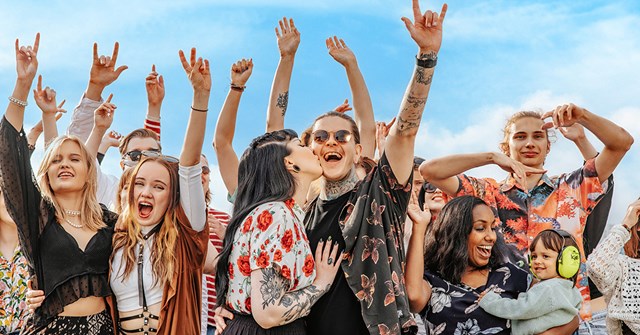 Festareilla oleva yleisö juhlii iloisena. Kaverukset, nuoripari sekä äiti pienen lapsensa kanssa pitävät hauskaa.