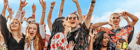 The crowd at the festivals is celebrating in the sunny weather and everyone is having a good time. Friends, a young couple and a mother with her small child stand out from the crowd.