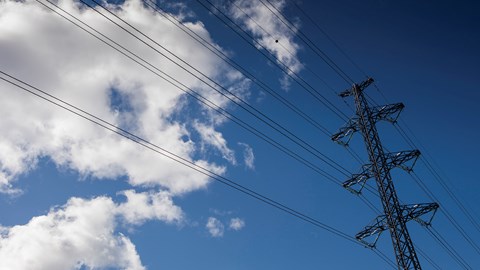 A power line from puffy clouds against the sky.