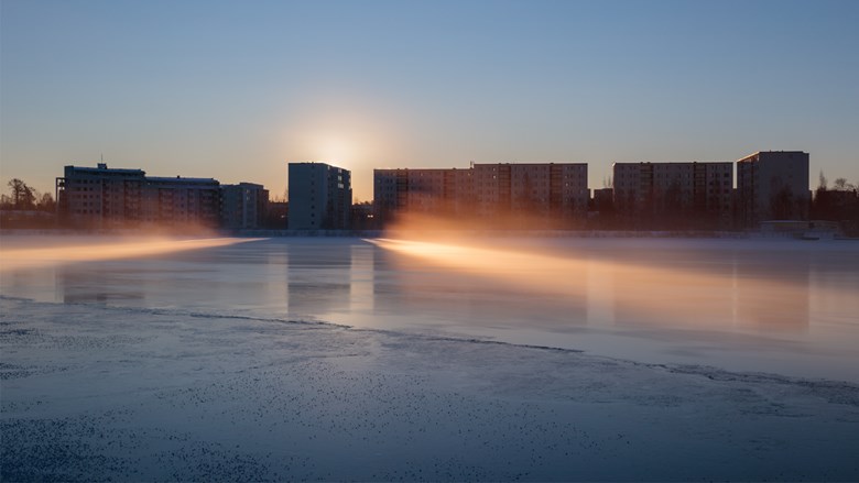Talvinen kuva Oulujoesta, jossa aurinko paistaa ja höyryä nousee joesta