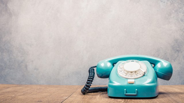 Old fashioned landline phone on wooden table.