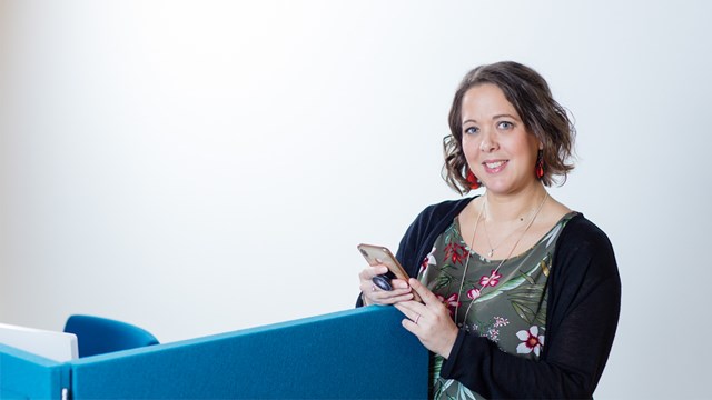 Oulun Energia employees pose with their smartphones in their hands in the office.