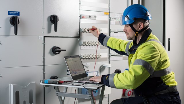 A Oulun Energia employee dressed in work clothes takes electrical measurements.