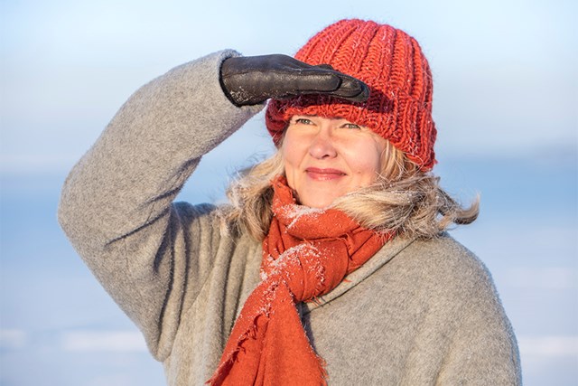 Oulun Energian työntekijä katsoo kaukaisuuteen ja varjostaa kädellään aurinkoa.